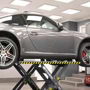 Vehicle raised on the extended platforms of a BendPak MDS-6LP mid-rise scissor lift to reach additional OEM lifting points.